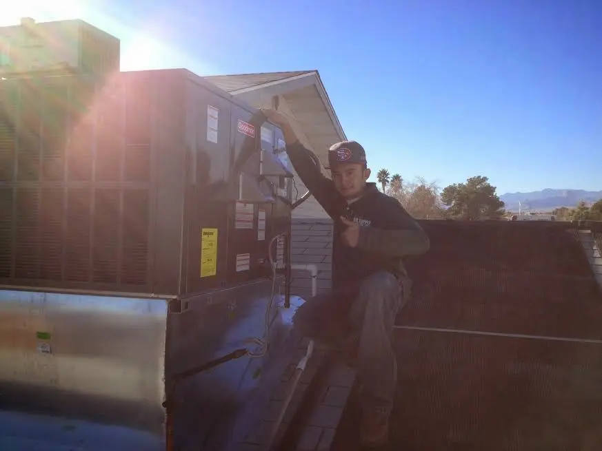 HVAC technician performing AC Tune-Up on a rooftop unit in Heath